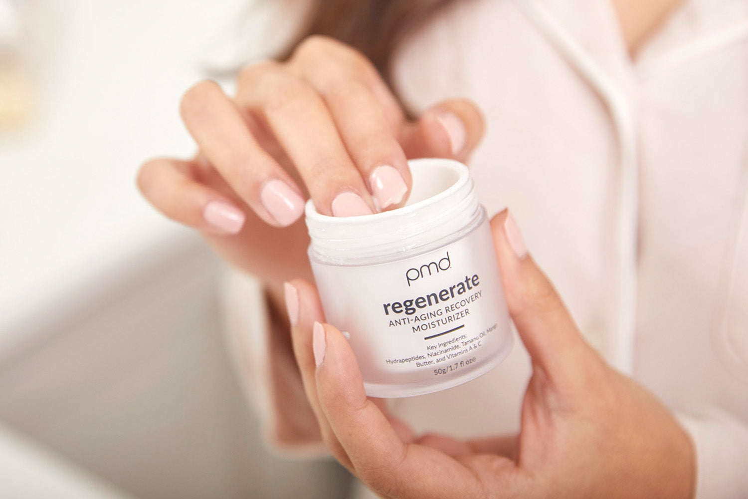 woman with fingers in regenerate moisturizer jar