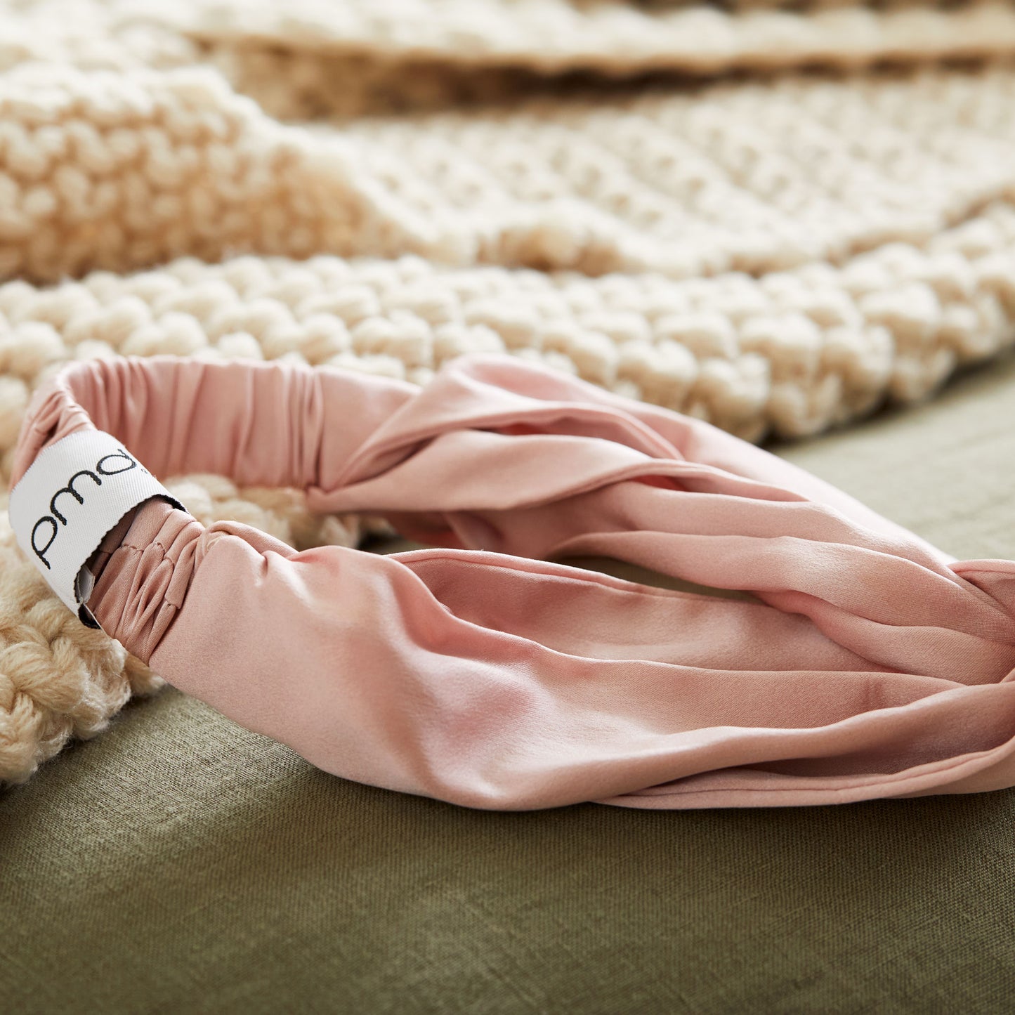 5008-HBROSE?silversilk headband in rose next to woven blanket