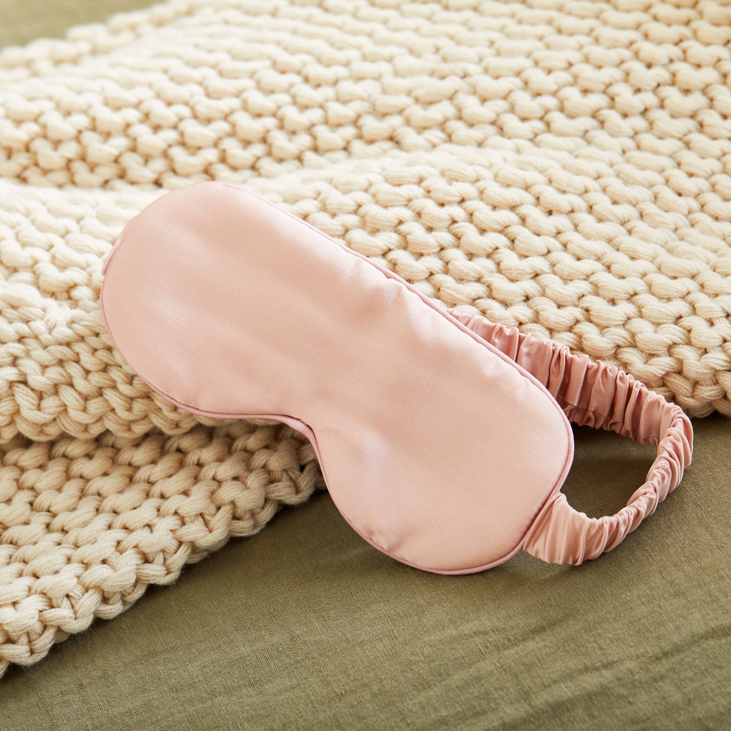 5008-SMROSE?Closeup of silversilk sleep mask in rose next to woven blanket