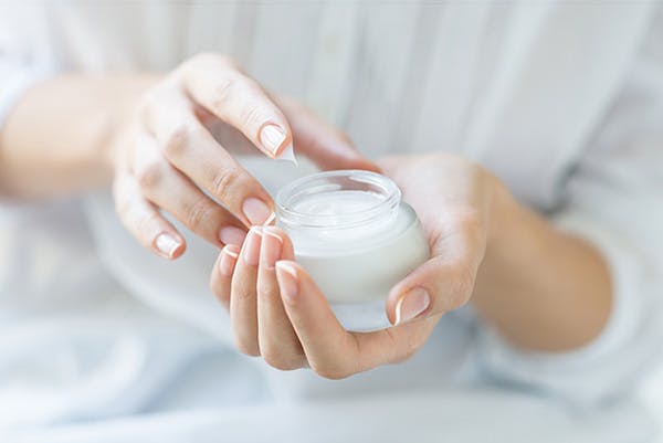 Woman dipping finger into sunscreen