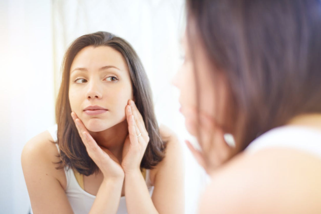 Woman looking at skin in mirror