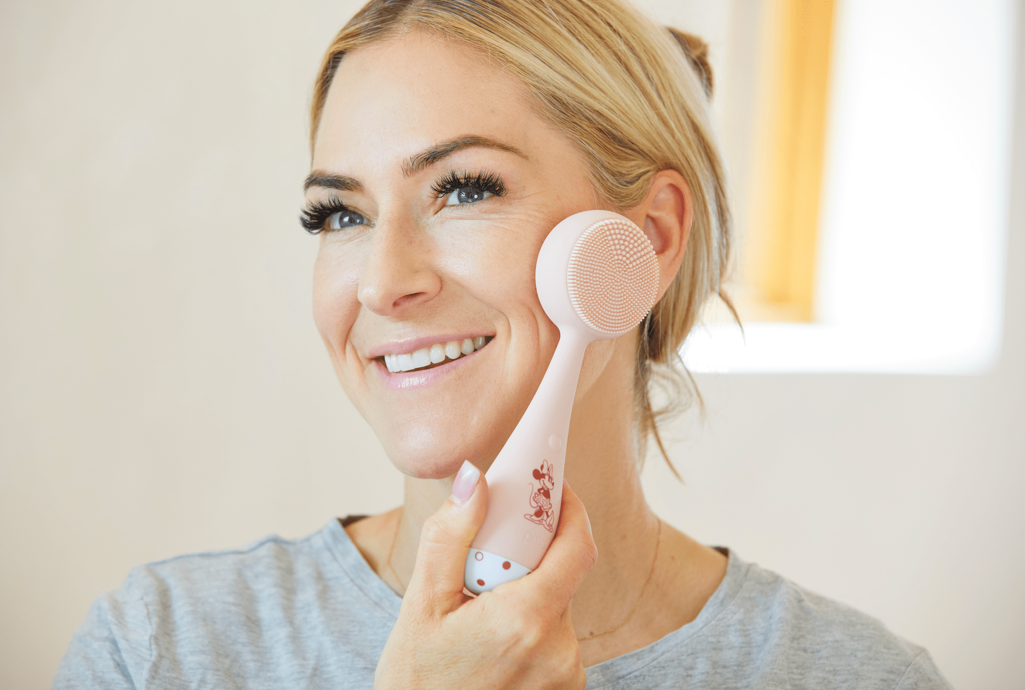 PMD Beauty founder using the PMD Clean device on her face, demonstrating gentle at-home cleansing to remove dirt, oil, and makeup for smoother, radiant skin.