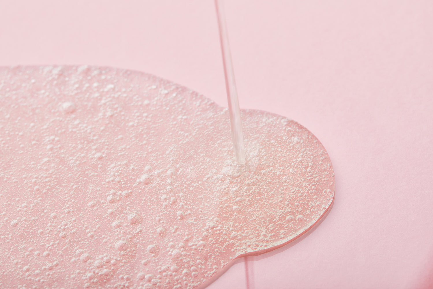 cleanser being poured on pink background