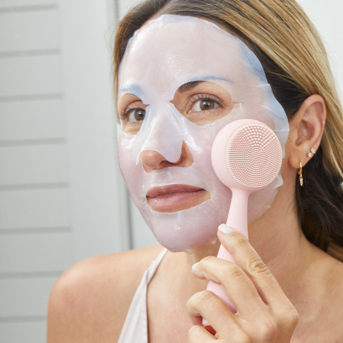 woman with sheet mask on using the back side of the PMD Clean Pro