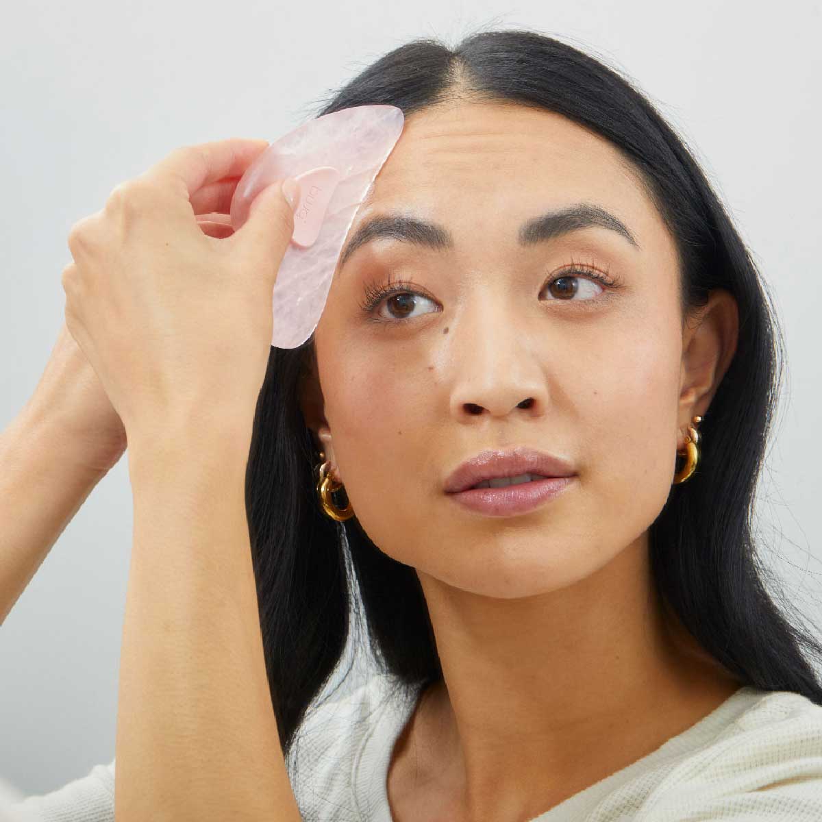 woman using gua sha on face