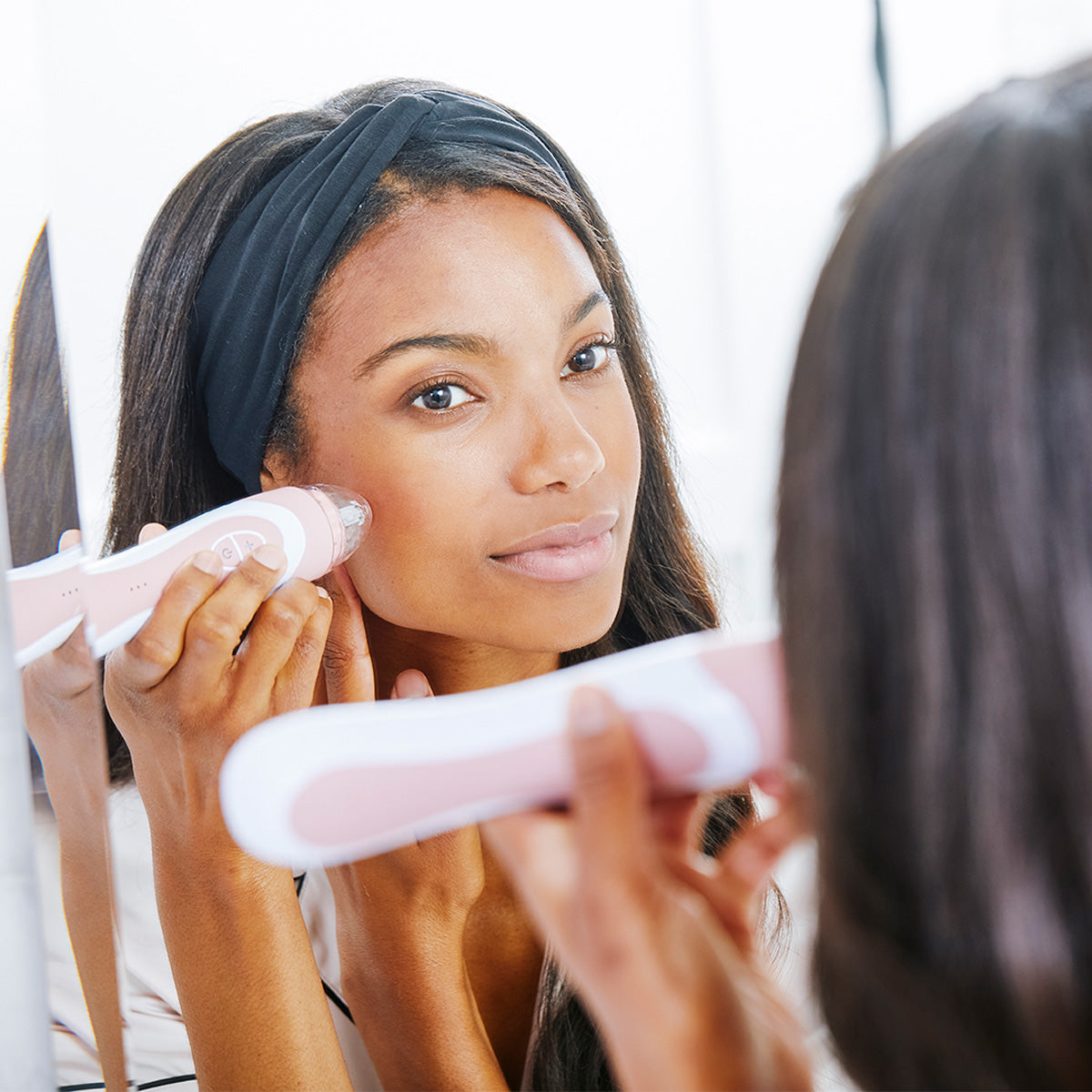 woman looking in mirror using personal microderm elite pro