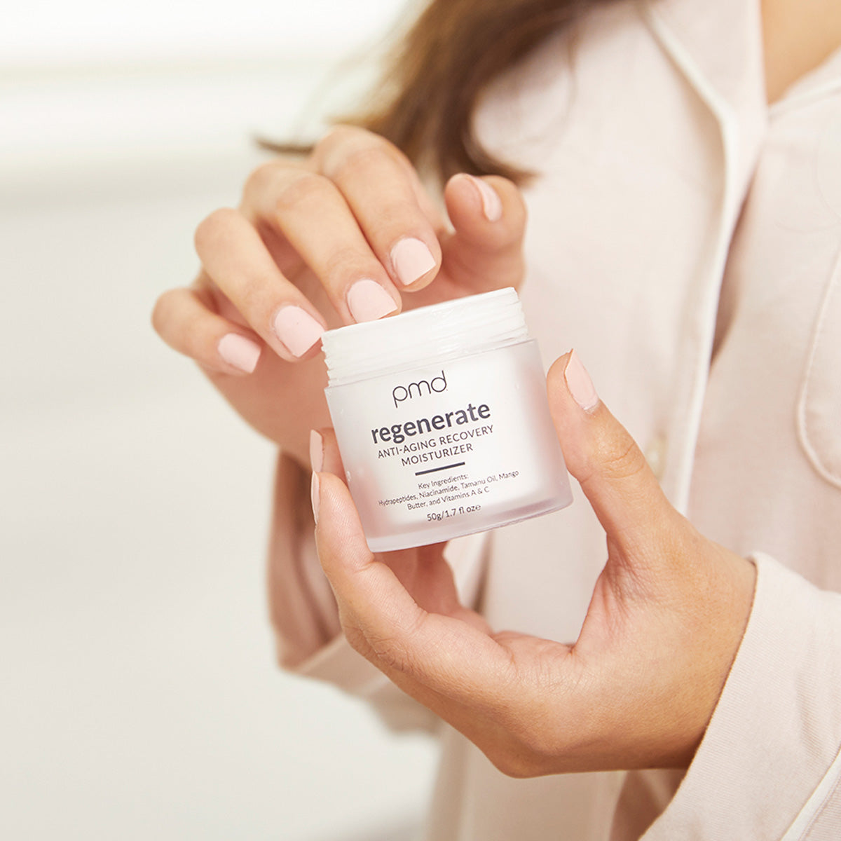 woman putting fingers in moisturizer jar