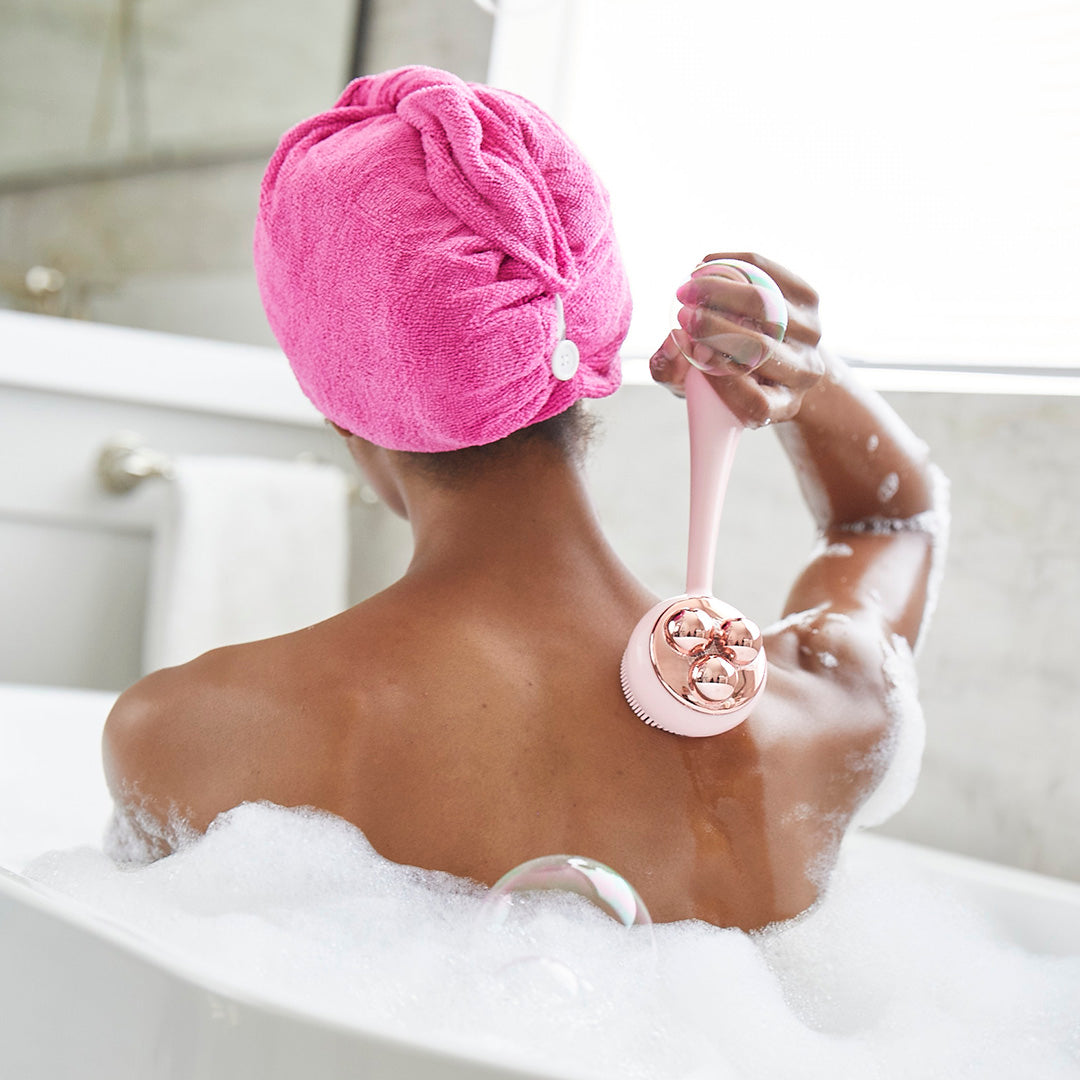 4003-Blush? Woman using PMD Clean Body in tub to cleanse her back